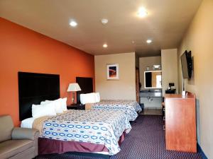 a hotel room with two beds and a flat screen tv at Budget Host Inn in Jourdanton