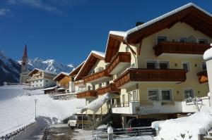 a building on a snow covered mountain with a church at Apparthotel Sonnwies in Selva dei Molini