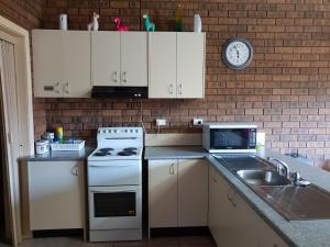a kitchen with a stove and a sink and a clock at Inara Apartment Mudgee in Mudgee