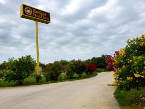 a street sign in the middle of a road with flowers at Budget Host Inn in Jourdanton