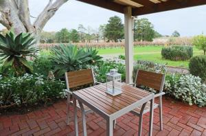 - une table en bois et 2 chaises sur la terrasse dans l'établissement Linger Longer Vineyard, à Willunga
