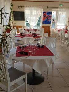 a dining room with white tables and white chairs at Le Melchior in Sainte-Terre