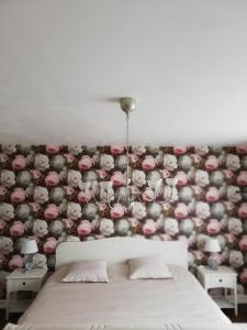 ein Schlafzimmer mit einem Bett und einer mit Blumen bedeckten Wand in der Unterkunft Chambres d'hôtes Sandrine Louis in Phalsbourg