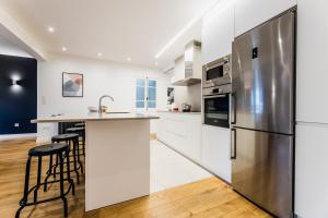 a kitchen with white cabinets and a stainless steel refrigerator at ZABALETA SUITE APARTMENT in San Sebastián
