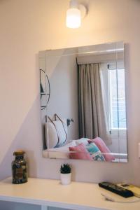 a mirror on a wall above a counter with a bed at Theodora Rooms in Poros