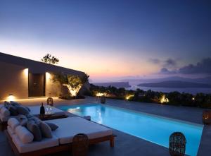 a villa with a swimming pool at night at Melidonia Suites in Akrotiri