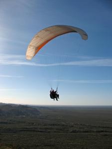 a person flying through the air with a parachute at De a Dos in San Rafael