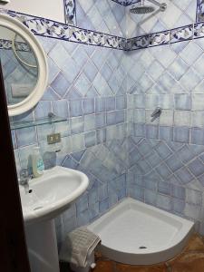 W wyłożonej niebieskimi kafelkami łazience znajduje się umywalka i toaleta. w obiekcie Les Amis w mieście Palinuro