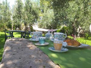 een tafel met bekers en borden met voedsel erop bij B&B MadaM in Faggiano