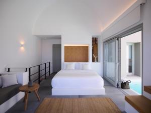 a bedroom with a white bed and a table at Melidonia Suites in Akrotiri