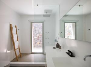 a white bathroom with a sink and a mirror at Melidonia Suites in Akrotiri