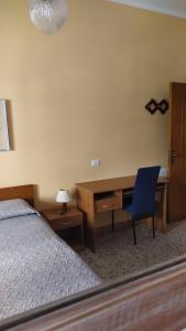 1 dormitorio con escritorio y 1 cama con silla azul en Affittacamere Da Priscilla, en Porto Torres