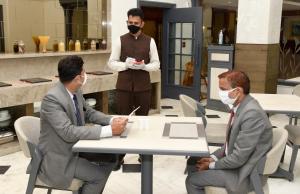 two men wearing masks sitting at a table with a man wearing a mask at Comfort Inn Sunset in Ahmedabad