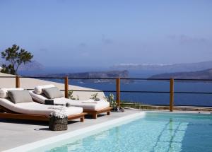 a swimming pool with lounge chairs next to a swimming pool at Melidonia Suites in Akrotiri