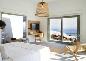 a bedroom with a bed and a tv and a balcony at Melidonia Suites in Akrotiri