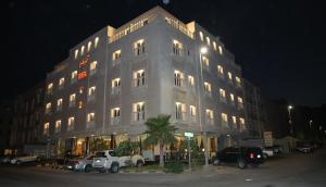 阿可賀巴的住宿－فندق سمأ الرفاع 2，一座白色的大建筑,前面有汽车停放