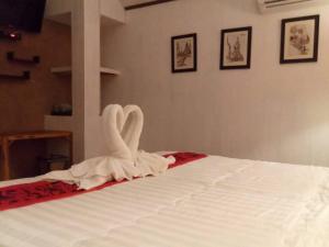 una cama blanca con una decoración de cisne en ella en Baan B&B Sukhothai, en Sukhothai