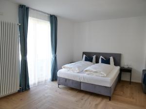 sypialnia z dużym łóżkiem i dużym oknem w obiekcie Apartments Sabine G w Meranie