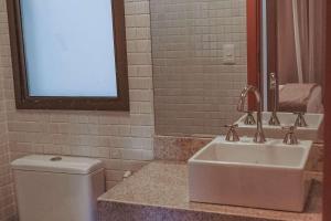 a bathroom with a sink and a toilet and a mirror at Samba Rio Convention & Residence in Rio de Janeiro