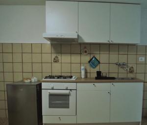a kitchen with a stove and white cabinets at Bilocale a due passi dal Gran Paradiso in Locana