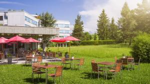 un grupo de mesas y sillas con sombrillas rojas en Hotel Allegro Einsiedeln, en Einsiedeln