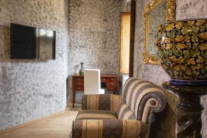 - un salon avec une chaise et une télévision dans l'établissement La Togata Hotellerie de Charme - Relais il Pozzo, à Montalcino