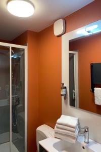 W łazience znajduje się toaleta, umywalka i lustro. w obiekcie Logis Hôtel le Regis w mieście Mont-Dore