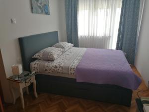 una camera da letto con un letto con una coperta viola e una finestra di Lino Apartments a Rovigno (Rovinj)