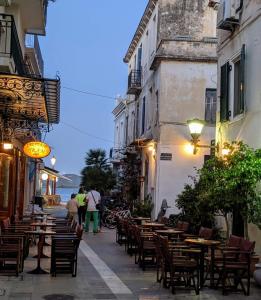 a street with tables and chairs and people walking down a street at Ionion Studios in Kanali +42 photos
