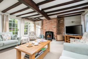 a living room with a table and a fireplace at Beck Cottage, Wood Green, New Forest UK in Breamore