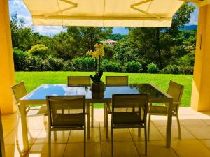 uma mesa de vidro com cadeiras e um vaso sobre ela em La Gaude, villa 6 personnes-jardin-piscine-vue dégagée au calme em La Gaude