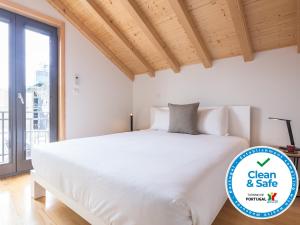 Cette chambre comprend un lit blanc et une grande fenêtre. dans l'établissement InSitu Trindade by Guestify, à Porto