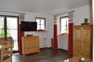 uma sala de estar com televisão e cortinas vermelhas em Am Sonneneck - Wohnung 7 em Ruhpolding