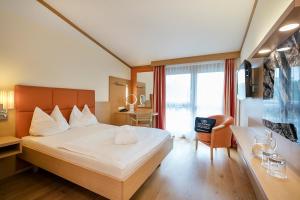 a hotel room with a large bed and a desk at Quellenhotel Heiltherme Bad Waltersdorf - 2-Thermenresort in Bad Waltersdorf