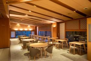 un restaurant avec des tables, des chaises et des fenêtres dans l'établissement onsen hotel OMOTO, à Matsumoto