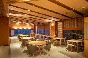 a restaurant with tables and chairs and windows at onsen hotel OMOTO in Matsumoto