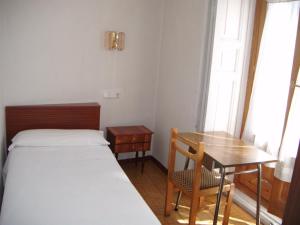 een kleine kamer met een bed, een bureau en een tafel bij Hostal Tudescos in Madrid