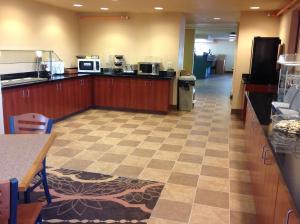 a cafeteria with a kitchen with a counter top and a unintention at Richland Inn and Suites in Sidney