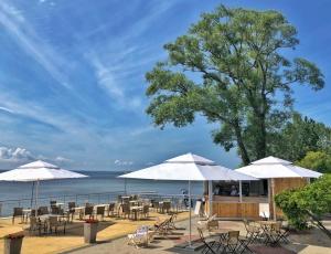 a restaurant with tables and umbrellas next to the water at Ośrodek Delfin Rewita in Jurata