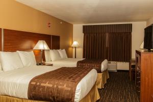 a hotel room with two beds and a television at Richland Inn and Suites in Sidney