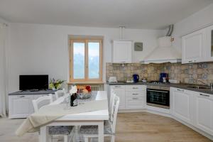 eine Küche mit weißen Schränken sowie einem Tisch und Stühlen in der Unterkunft casa doss in Tremosine sul Garda