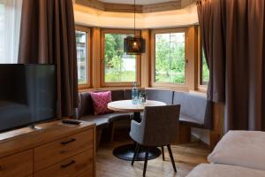 sala de estar con mesa, TV y cama en Olympia-Relax-Hotel Leonhard Stock, en Finkenberg