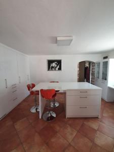 een keuken met een witte tafel en twee rode stoelen bij Istrska kamnita hiša Sončni Medulin in Medulin