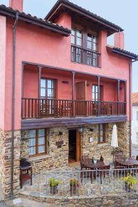 a red house with a balcony and tables and chairs at La Quintana de Somao, Casa Quintana in Somado