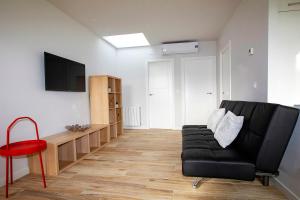 Apartamentos Salitre في سوتو دي لا مارينا: غرفة معيشة مع أريكة سوداء وكرسي احمر