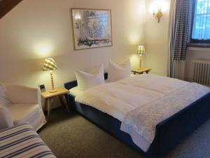 ein Schlafzimmer mit einem großen weißen Bett und einem Stuhl in der Unterkunft Ferienwohnungen Elisabeth am See in Rottach-Egern