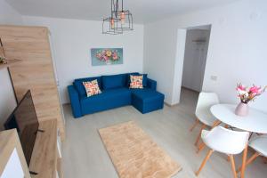 a living room with a blue couch and a table at Apartament Delora View in Bumbeşti-Jiu