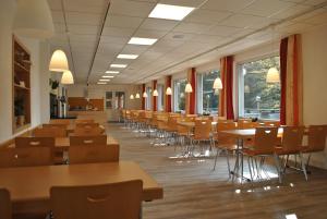 a cafeteria with tables and chairs and windows at Flambacher Mühle in Clausthal-Zellerfeld