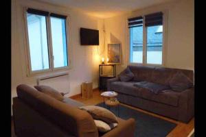 a living room with a brown couch and a fireplace at Cauterets coeur village grand duplex 11 couchages in Cauterets