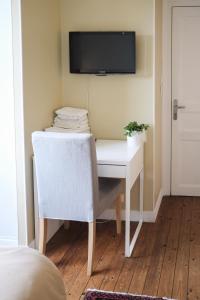 einen weißen Schreibtisch mit Stuhl und einen TV an der Wand in der Unterkunft Pension de Kerioual in Roscoff